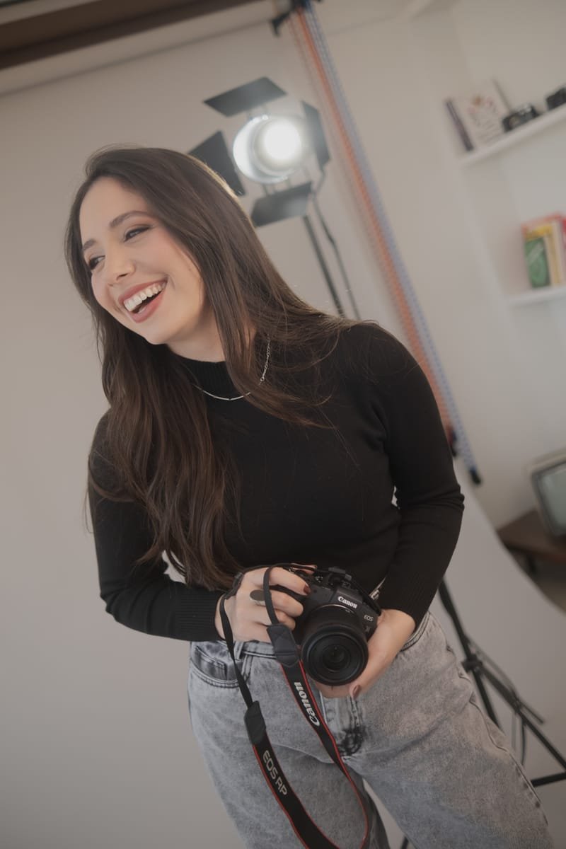 Bruna Gral rindo, de pe, com a camera na mao durante um ensaio